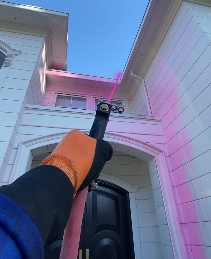 Soft Washing Service Picture shows a wash technician spraying soap with soft / low pressure on a house exterior during a soft wash cleaning job in Vancouver